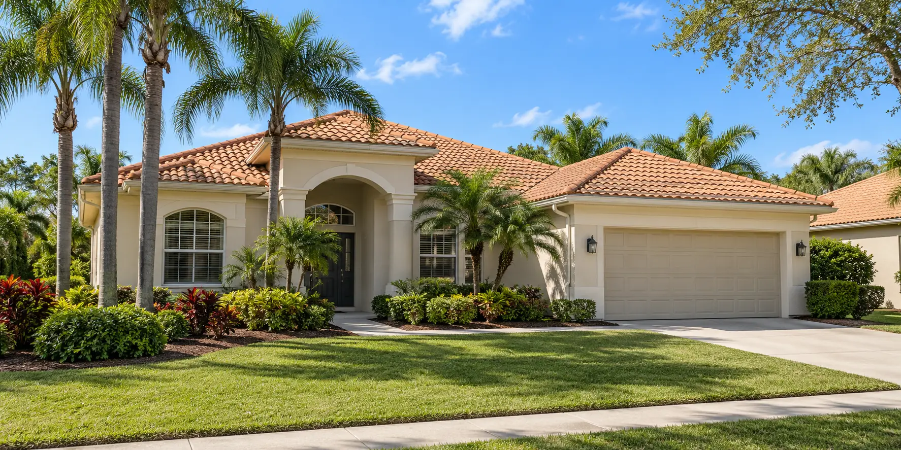 Light stucco Florida home with a tile roof and tropical landscaping