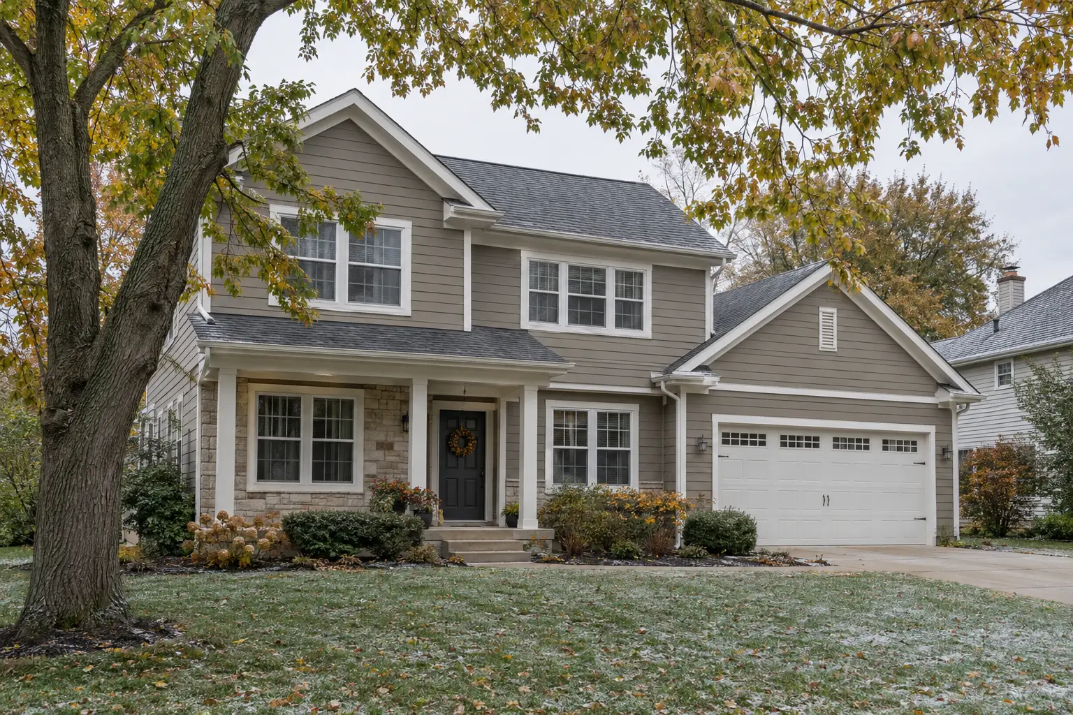 Two-story Midwest home finished in a mid-tone greige with autumn trees